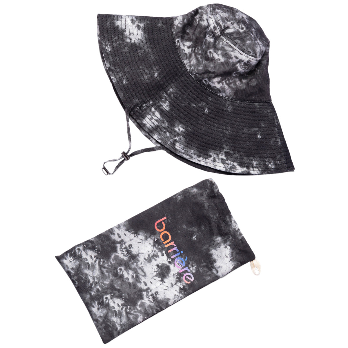 A black-and-white tie-dye sun hat with a wide brim and an adjustable chin strap, paired with a pouch. Both items share a black splotch tie-dye pattern on a white background. The brand name "barrière" is visible on the pouch.