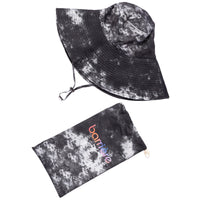 A black-and-white tie-dye sun hat with a wide brim and an adjustable chin strap, paired with a pouch. Both items share a black splotch tie-dye pattern on a white background. The brand name "barrière" is visible on the pouch.