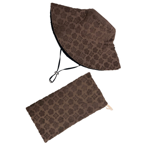 Reversable brown sun hat with an adjustable strap, accompanied by a matching bag. Both items are placed on a light grey background.