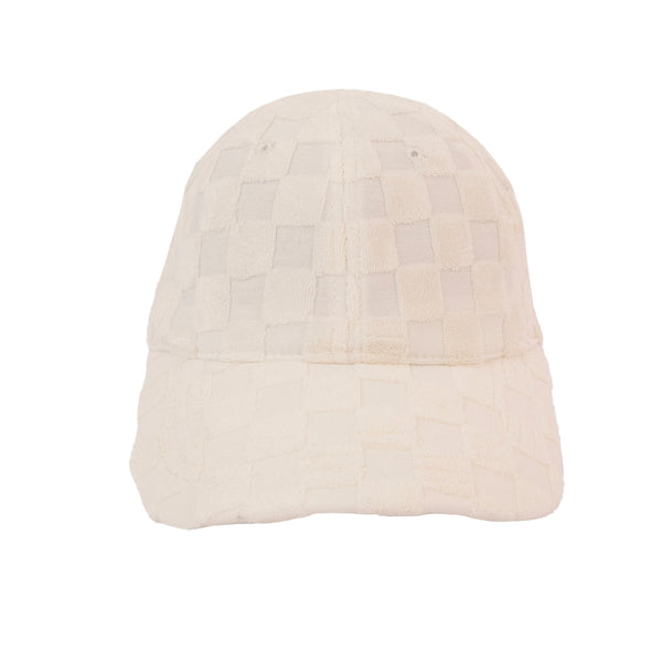 A light-colored baseball cap with a checkered texture.  The hat is displayed against a plain, light grey background.