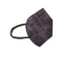 A single black face mask with a textured pattern, lying flat on a light-colored surface. The mask has ear loops on both sides.