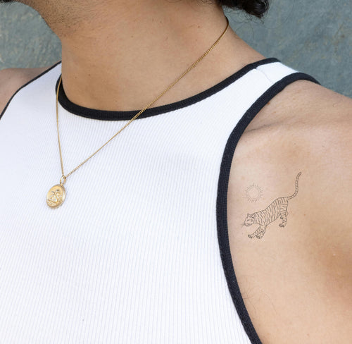 An individual wearing a black 'Daily Defense' patch on their front shoulder, near the collarbone, which has two small images on it.