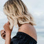 An individual near the sea wearing a ‘CALL OF BEAUTY’ vitamin patch on their shoulder.