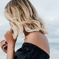 An individual near the sea wearing a ‘CALL OF BEAUTY’ vitamin patch on their shoulder.