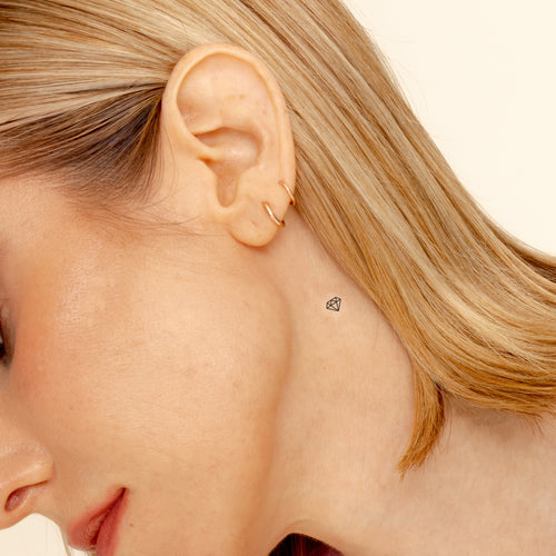 A ‘CALL OF BEAUTY’ vitamin patch worn an individual's neck  near behind her ear.