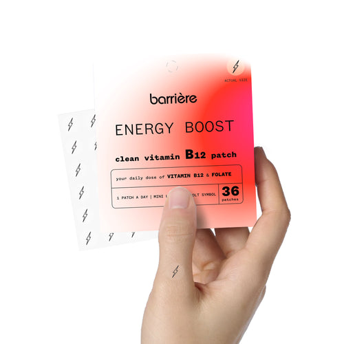 An individual hand holding the packet of 36 ‘ENERGY BOOST’ patches, with one patch on thumb of the right hand. The 36 patches are slightly visible, angled out from the side of the packaging.