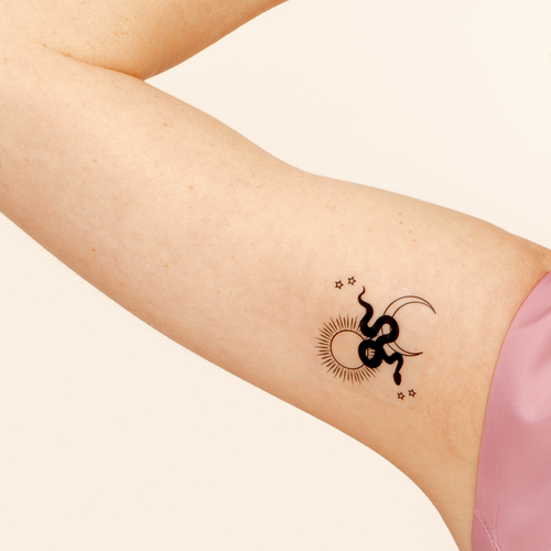 Close-up of a person’s arm with a vitamin patch featuring a stylized sun with rays extending outward and a crescent moon within the sun’s circle.
