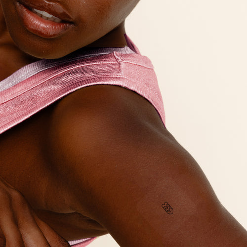 An individual wearing a small black ‘daily defense’ patch on their arm.