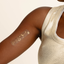 A person's arm with an adhesive patch with gold sun, moon and stars constellation features.