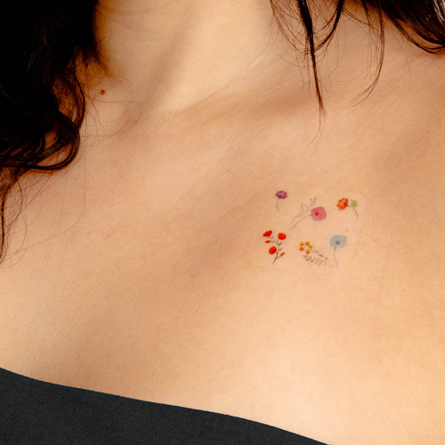 An individual’s collarbone with a patch that features various colorful designs resembling small fruits and flowers.