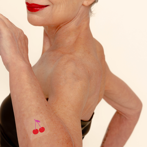 A vitamin patch placed on the arm, featuring a design with two cherries.