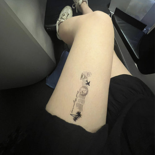 Close-up of a thigh with a black vitamin patch of a palm tree, mountain, and airplane post card feature.