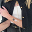 A person’s arm with a vitamin patch applied to it. The patch features printed images of white and gold shells and black leaves.